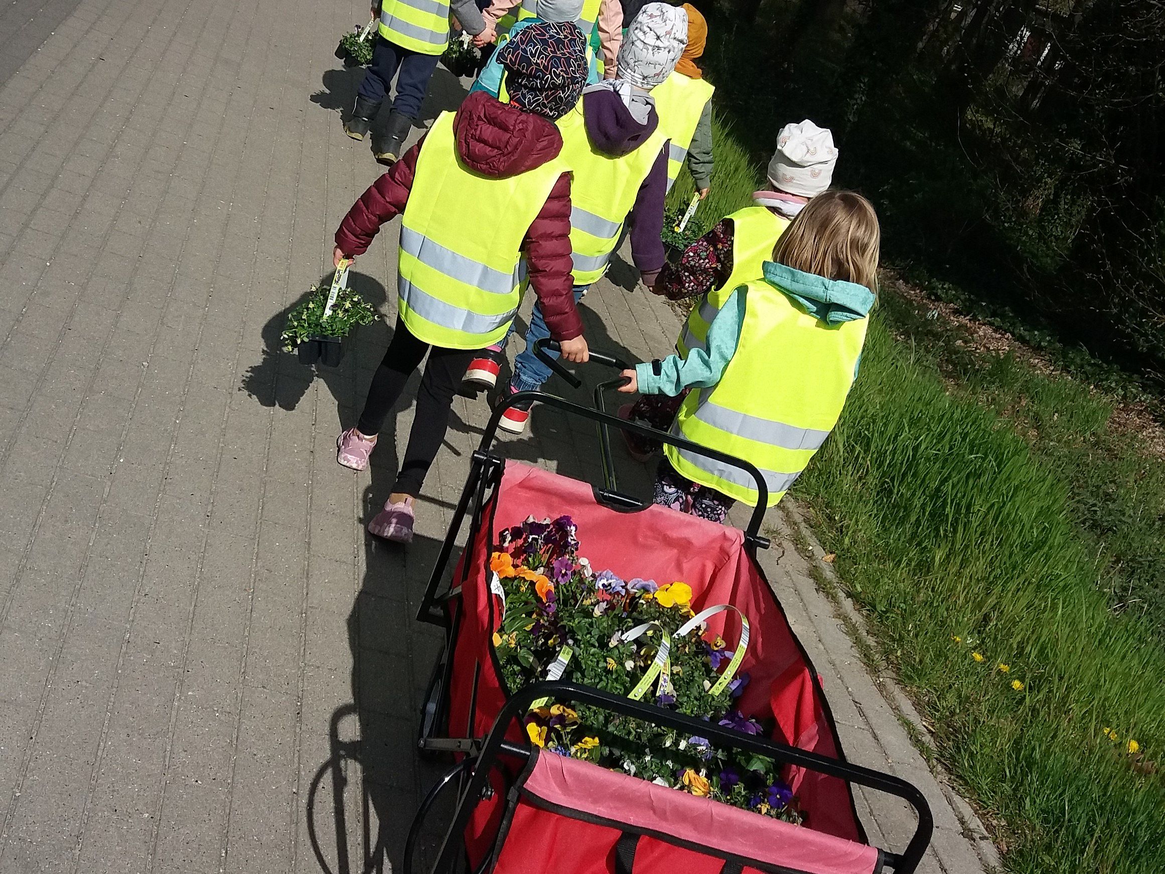 Bild zeigt Kinder mit dem Bollerwagen voller Blumen