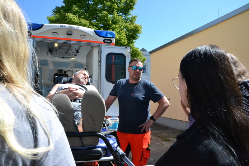 Bild zeigt Rettungsassistent René Mauch und Teilnehmer des Jobtages am Rettungswagen